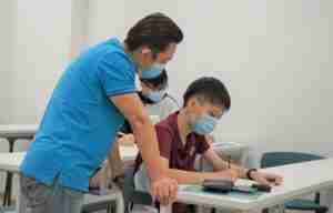 Mr Roger gives close attention to student during English class