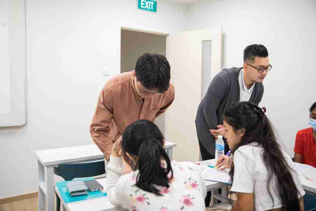 tutors and students in a classroom for General Paper, with Mr Liew and Mr Chia helping students closely