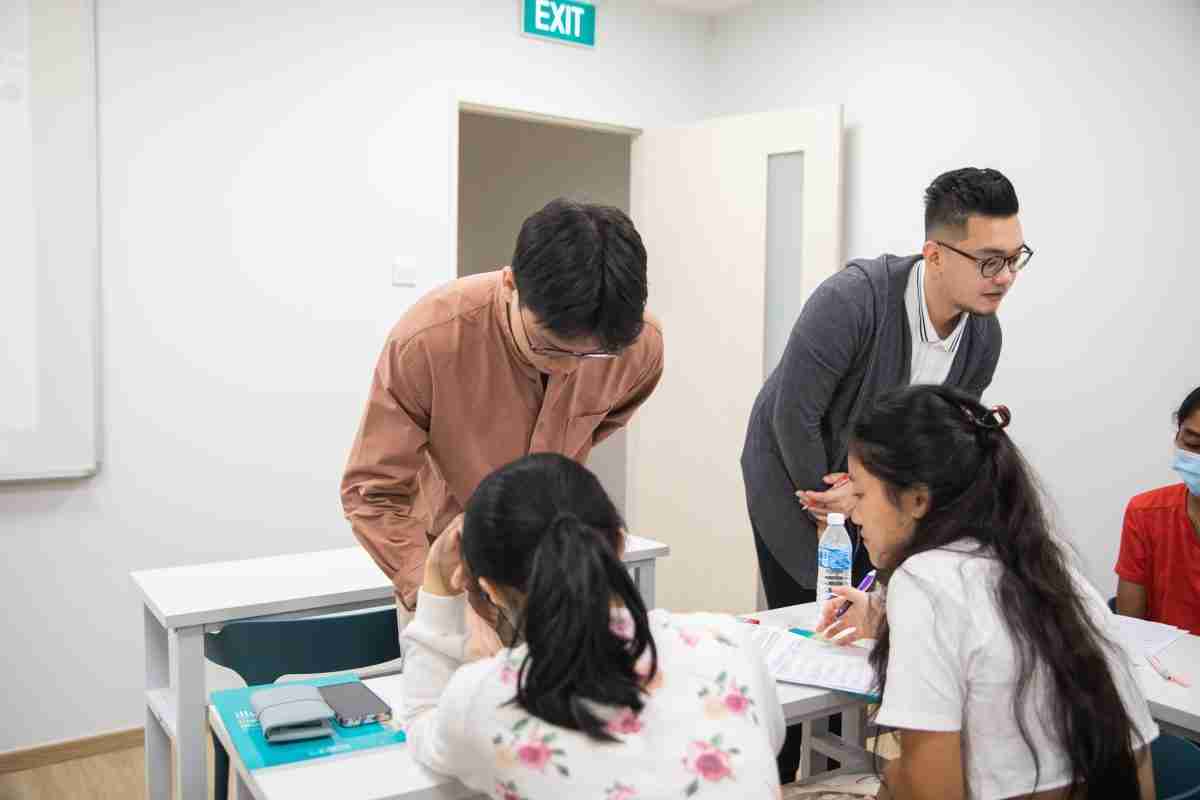 tutors and students in a classroom for General Paper, with Mr Liew and Mr Chia helping students closely