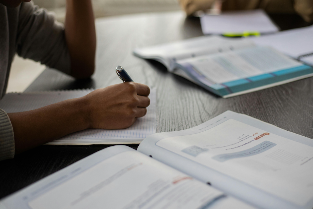A secondary school student with a notepad and textbooks before them as they study under the FSBB system.